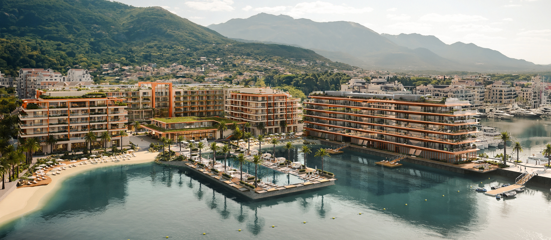 Aerial shot of the Synchro Yards area in Porto Montenegro, highlighting upscale waterfront buildings, pool areas, and a mountain landscape.