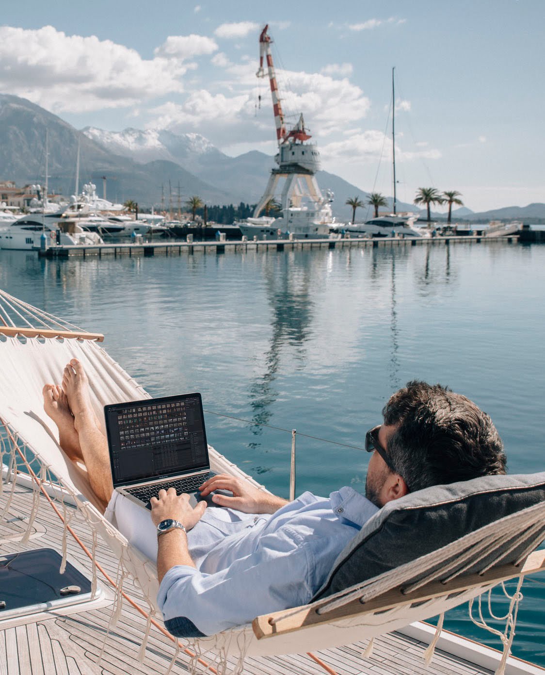 Man working on laptop next to porto montenegro marina