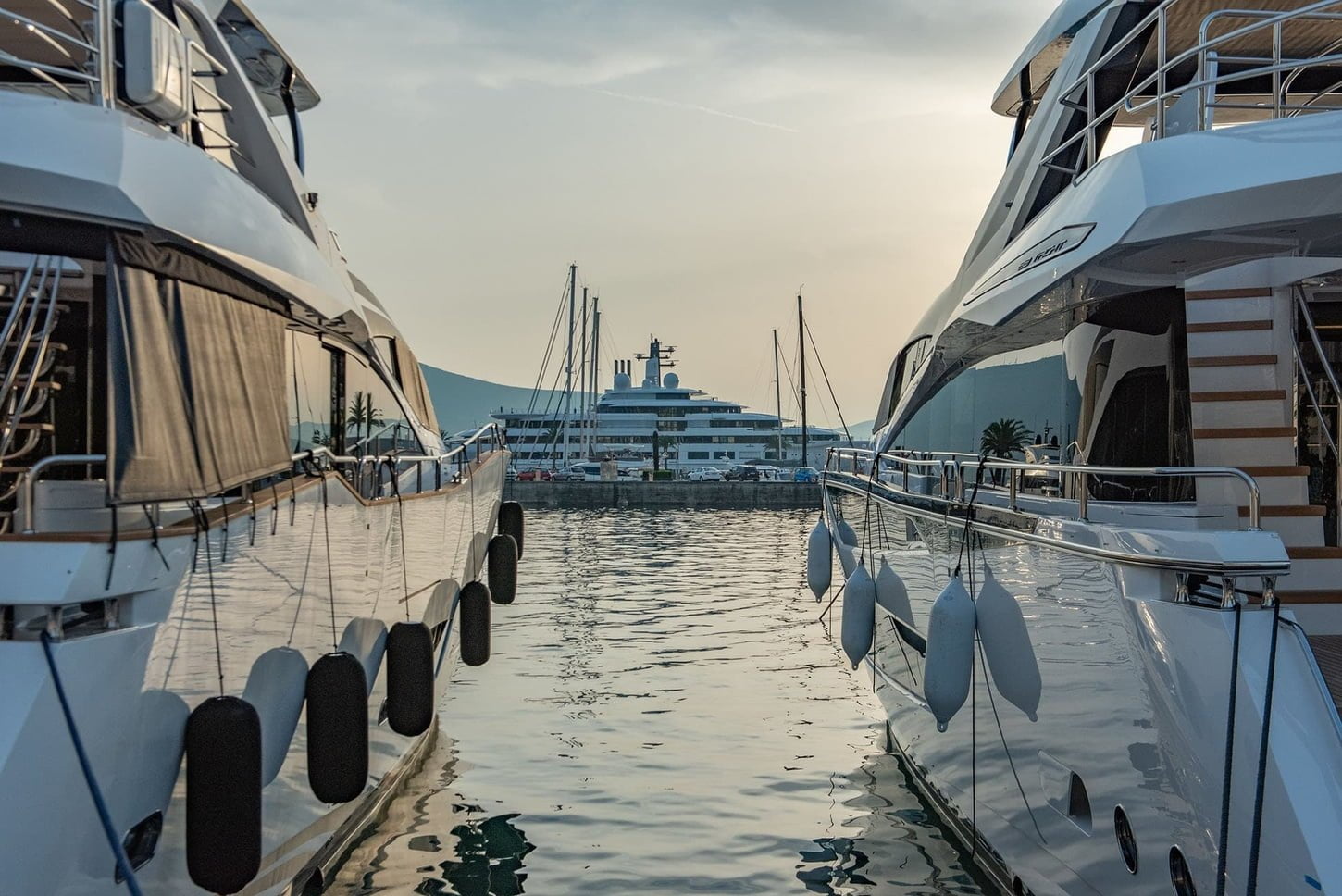 Two white yachts docked at the water's edge in Porto Montenegro marina in Tivat, creating a picturesque scene of tranquility and luxury.