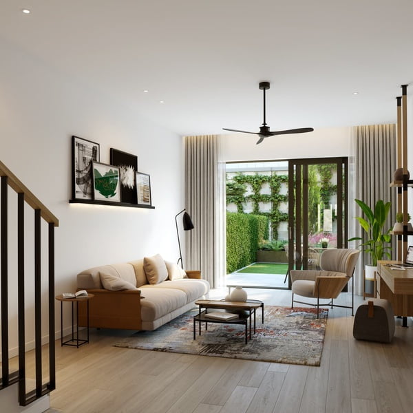 A contemporary living room with a beige couch, wooden furnishings, and artwork on the wall, opening up to a garden through glass doors.