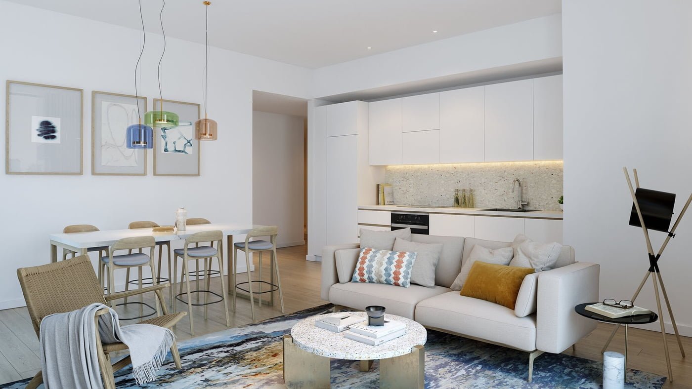 Open-plan living space with a minimalist white kitchen, a dining area with a white table and modern stools, and a cosy sitting area with a cream sofa.