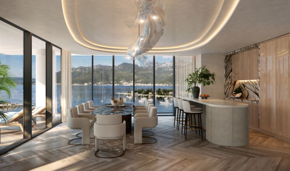 Elegant dining and kitchen area in AERIS Residences, Porto Montenegro, with panoramic floor-to-ceiling windows offering stunning views of the marina and mountains, complemented by modern furniture and a unique sculptural light fixture.