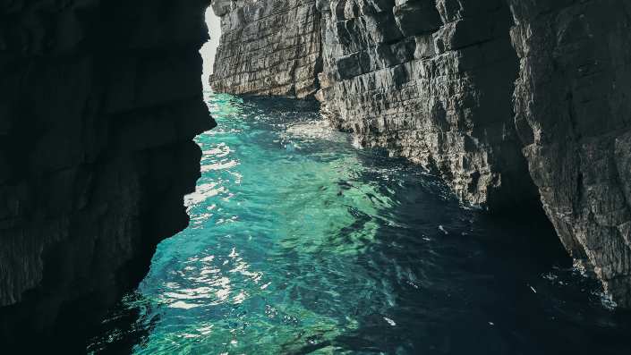 Inside the Blue Cave in Montenegro, glowing blue waters, create a mystical and serene atmosphere within the cave’s limestone walls.