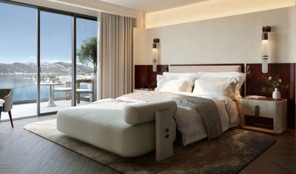 Elegant guest room in the IVO Residences at Porto Montenegro, featuring a plush bed, modern decor, and floor-to-ceiling windows providing a breathtaking view of the marina and mountains.