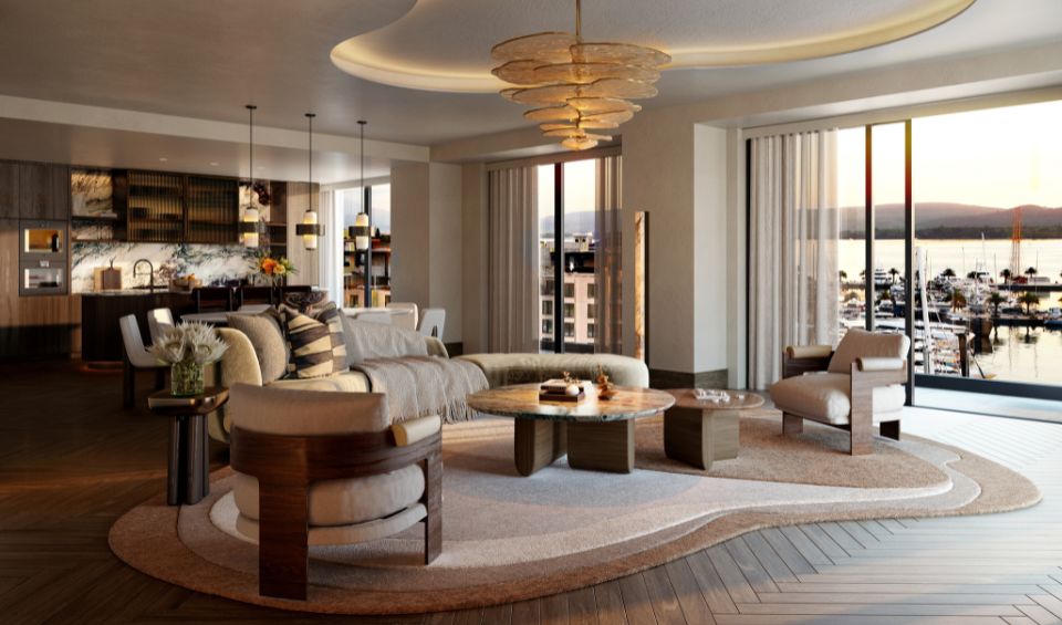 Interior view of the IVO Residences living room at Porto Montenegro, featuring a modern design with a luxurious kitchen island, elegant furnishings, and large windows overlooking the marina at sunset.