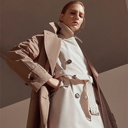 Woman standing in trench coat looking down