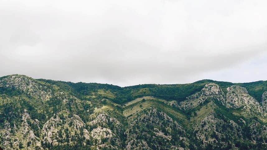 Rugged, verdant mountains under an overcast sky, illustrating the natural, untouched landscape.
