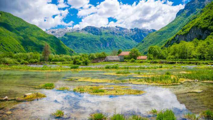 A stunning view of the Prokletije mountain range in Montenegro, featuring rugged peaks, a serene mountain lake, and pristine wilderness.