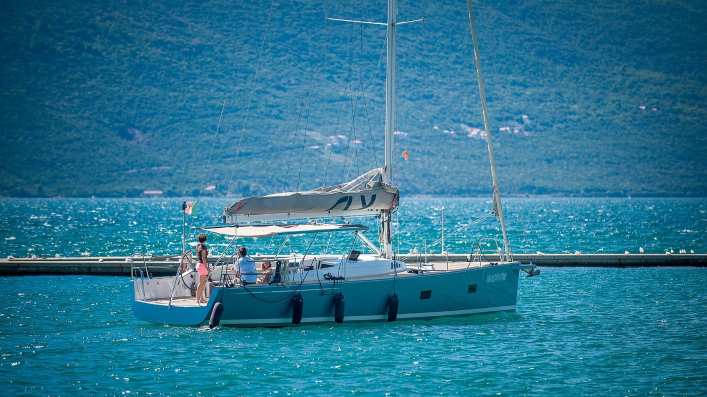 A beautiful scene of sailing in Tivat, featuring a sailboat on the calm waters with the stunning Tivat landscape and mountains in the background.