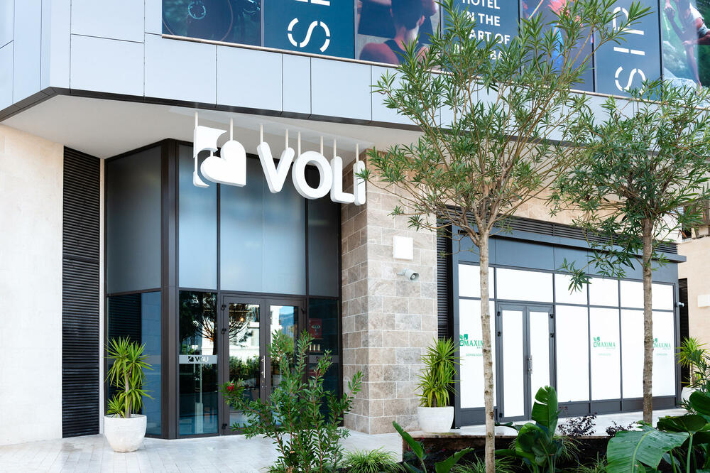 A modern market Voli located in Boka Place at Porto Montenegro, featuring a sleek, contemporary design with large glass windows and a clean, well-lit storefront. The setting exudes a luxurious ambiance, reflecting the upscale nature of the location.