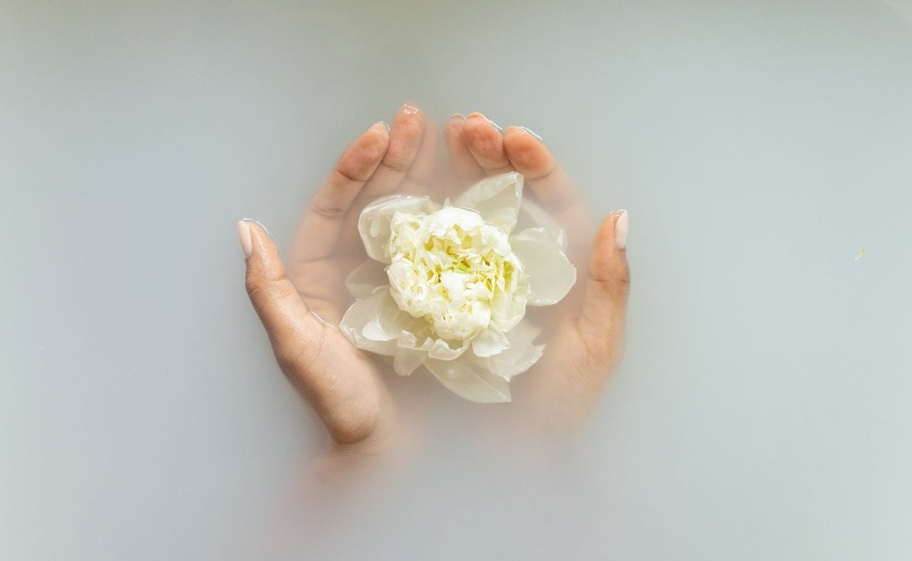 Women's hands holding a flower in a bath