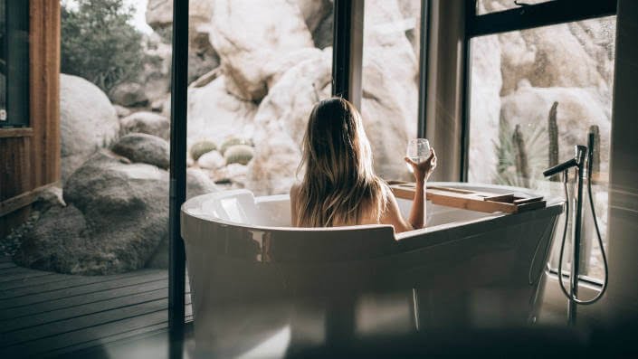 woman in bath tub with a glass of wine