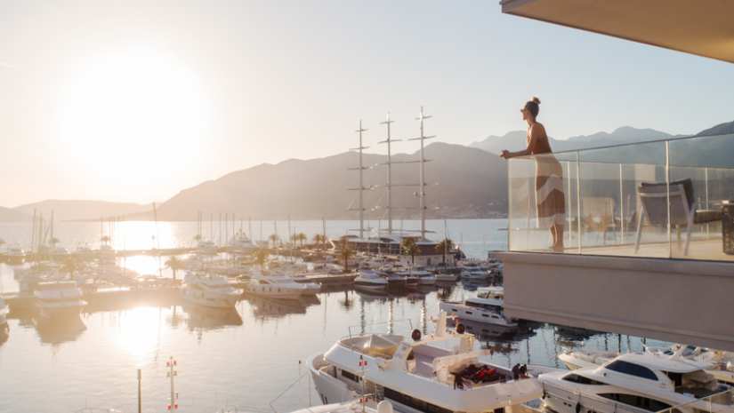 A woman enjoying a luxurious lifestyle aboard a yacht in Porto Montenegro, surrounded by stunning marina views