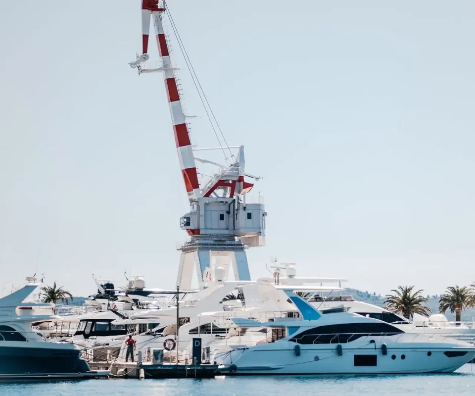 A striking red and white striped crane towering over luxurious yachts at Porto Montenegro Marina, symbolizing the area's rich maritime heritage and modern nautical lifestyle.