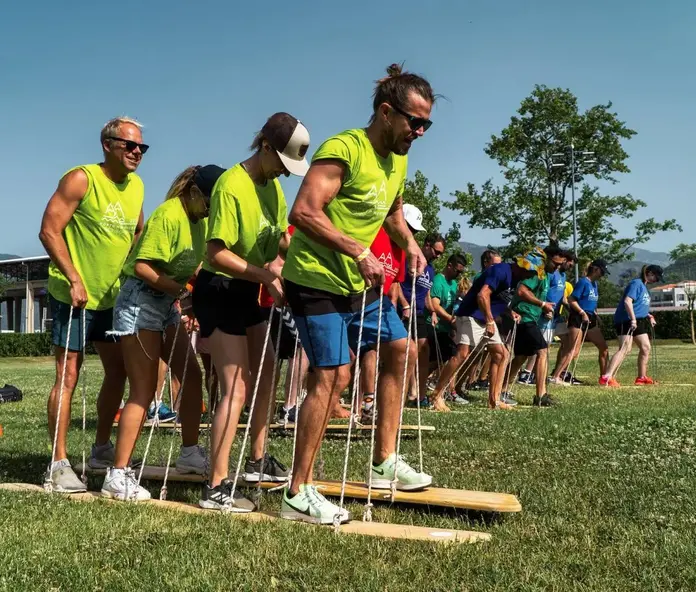A group of crew members participating in a fun team-building activity at Crew Club, balancing on wooden planks and working together to move in sync.