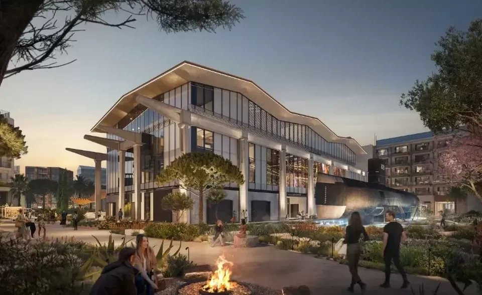 Modern architectural complex at dusk featuring a glass-walled building with high ceilings, surrounded by landscaped public spaces with people strolling and socializing, evoking a blend of cultural heritage and contemporary design.