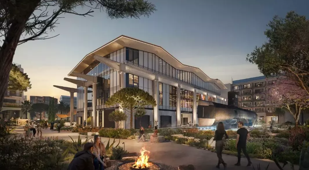Modern architectural complex at dusk featuring a glass-walled building with high ceilings, surrounded by landscaped public spaces with people strolling and socializing, evoking a blend of cultural heritage and contemporary design.