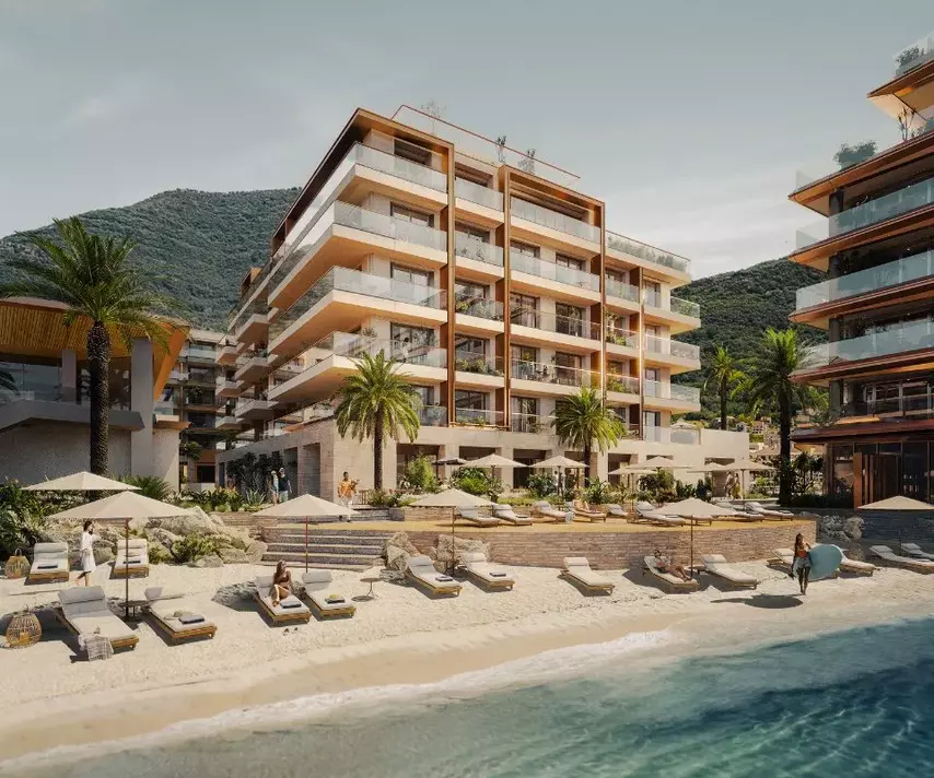 IVO Residences on a sunny day, featuring beachfront apartments with balconies, palm trees, and loungers.